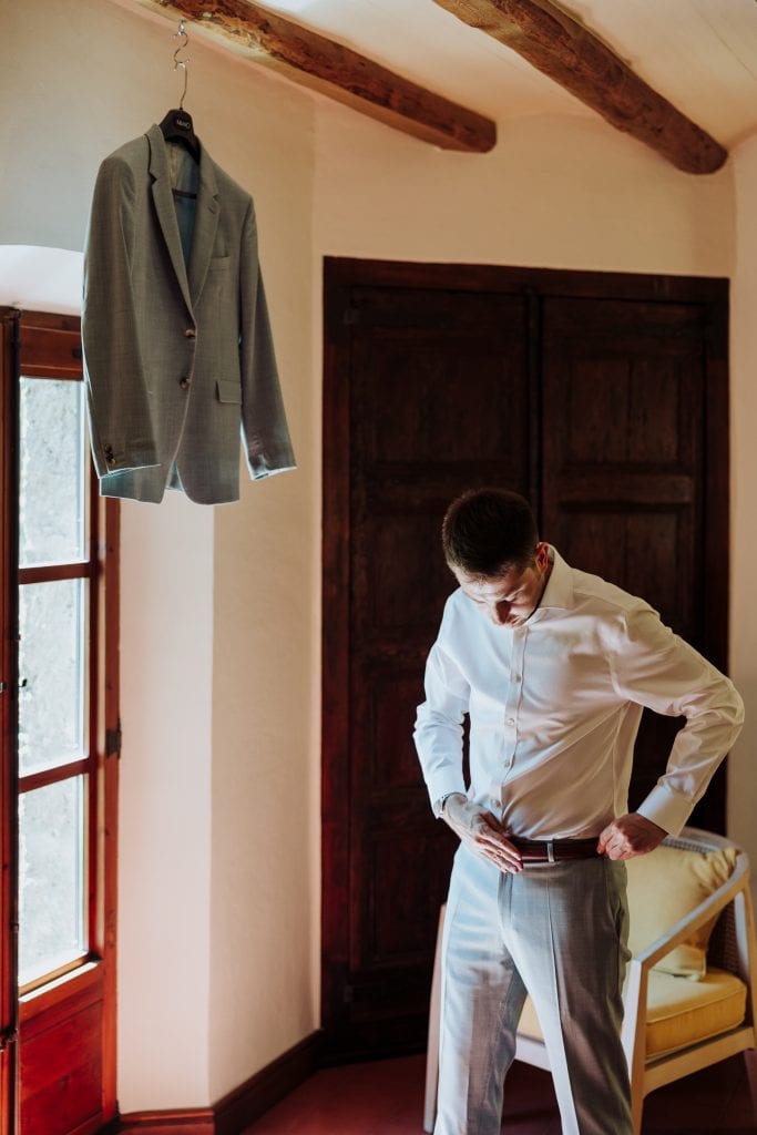 Traje de novio en habitación con ventana y armario, preparado para la boda en un entorno rústico y a.