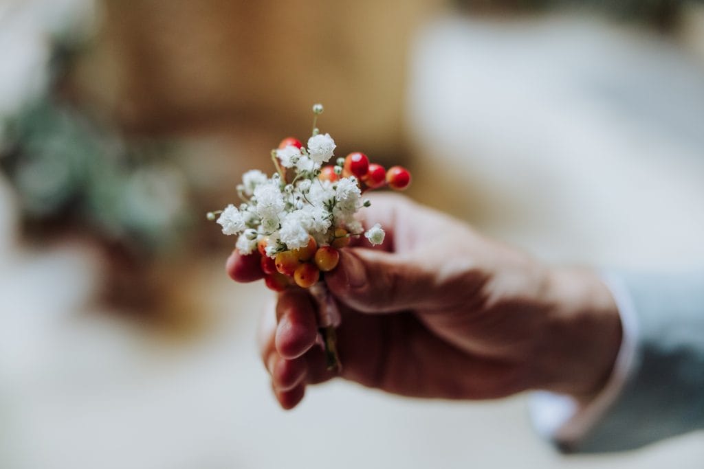 Ramo de flores naturales en la mano del novio en una boda atípica.