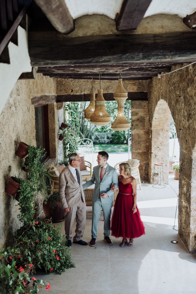 Boda en un espacio rústico con arquitectura de piedra y madera, con tres personas conversando en un.