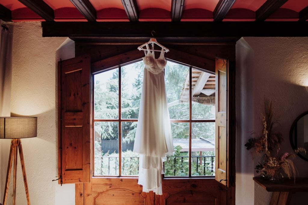 Vestido de novia colgado en la ventana con vista natural.