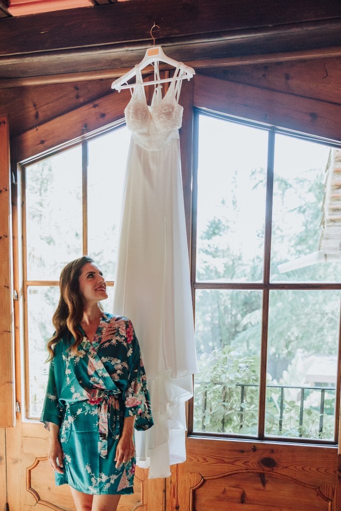 Vestido de novia elegante colgado en una habitación con paredes de madera y grandes ventanas.