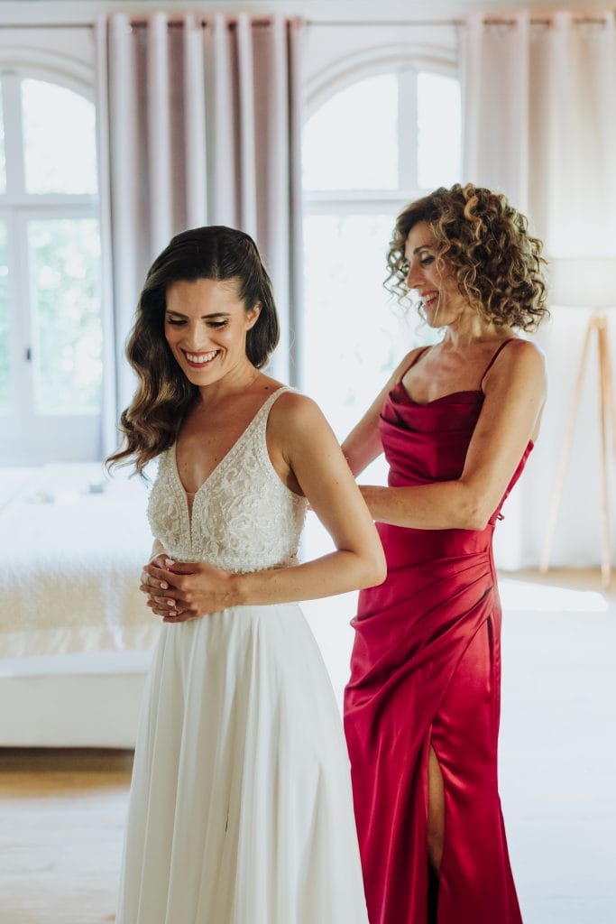 Vestido de novia y madre en preparación para la boda, en un ambiente luminoso y elegante.