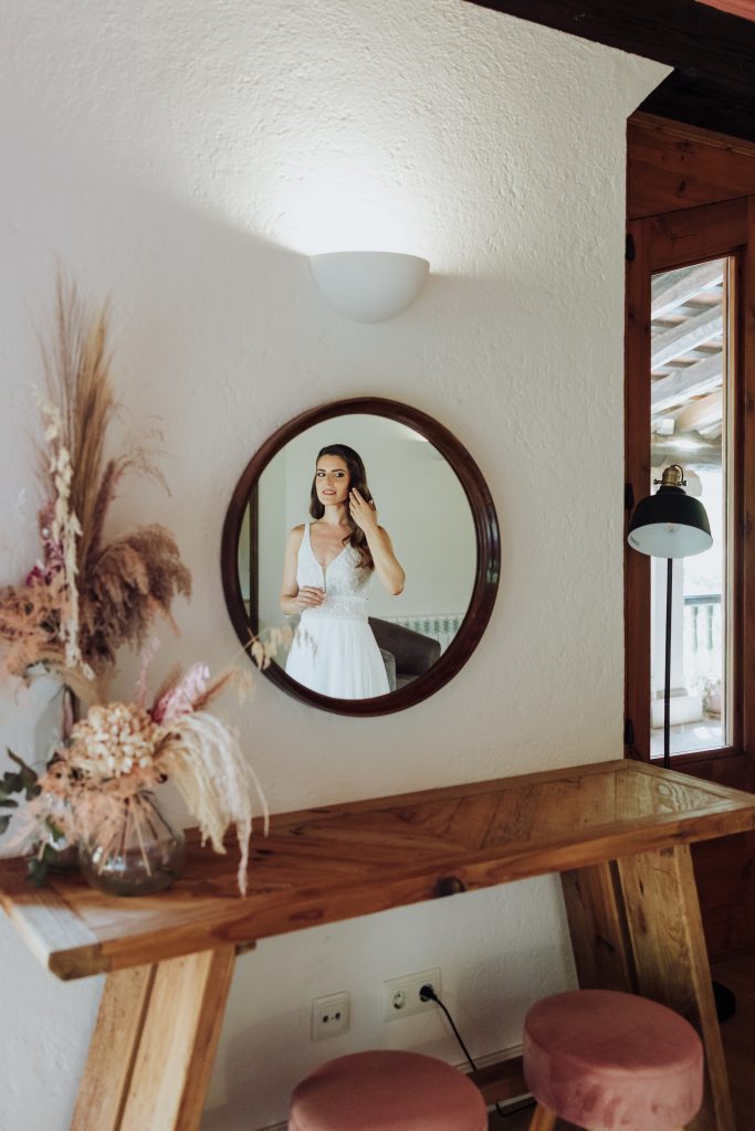 Vestido de novia en interior con espejo y decoración natural.