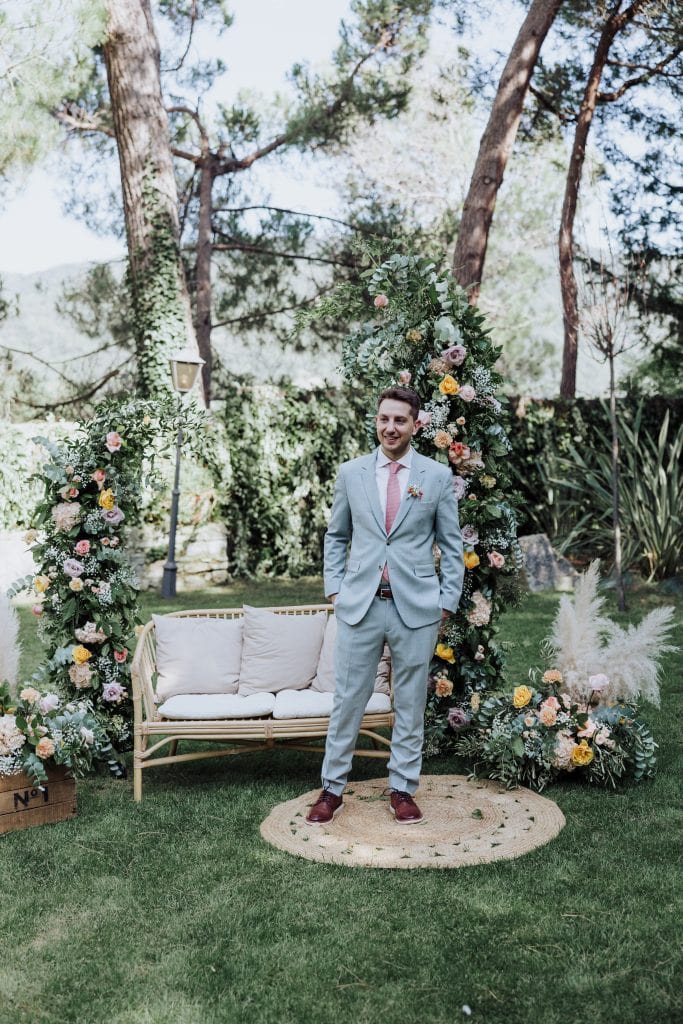 Boda en jardín con decoración floral y pareja vestida con traje formal. Escenario natural y romántic.