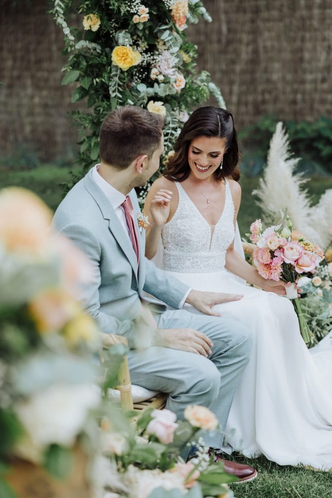 Boda en jardín con pareja feliz, rodeada de flores y decoración floral.