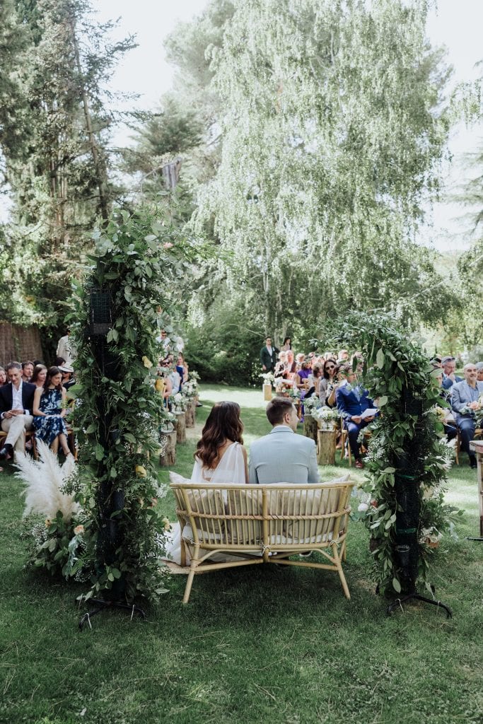 Boda al aire libre en un entorno natural con ceremonia en un arco decorado con flores y vegetación.