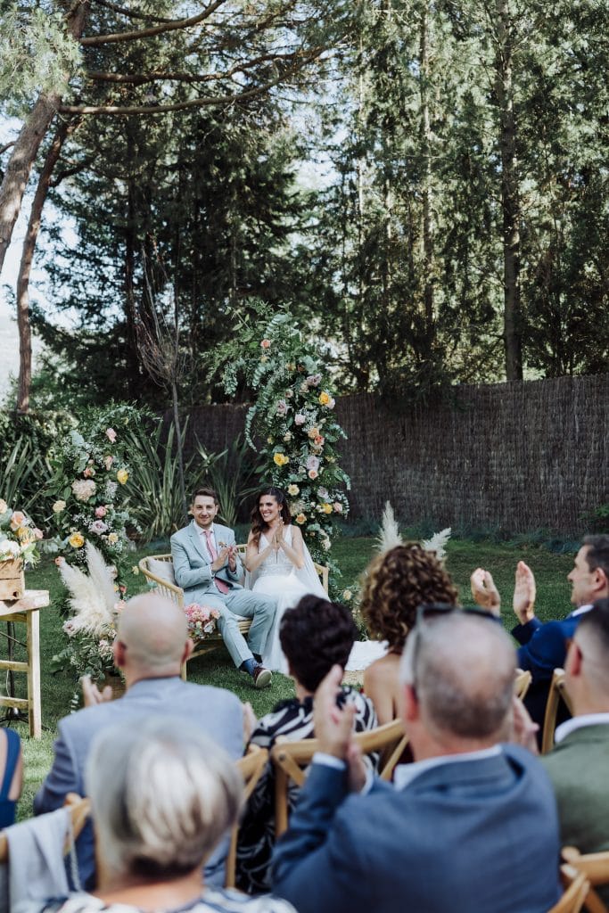 Boda en exterior con pareja y invitados en entorno natural y elegante.
