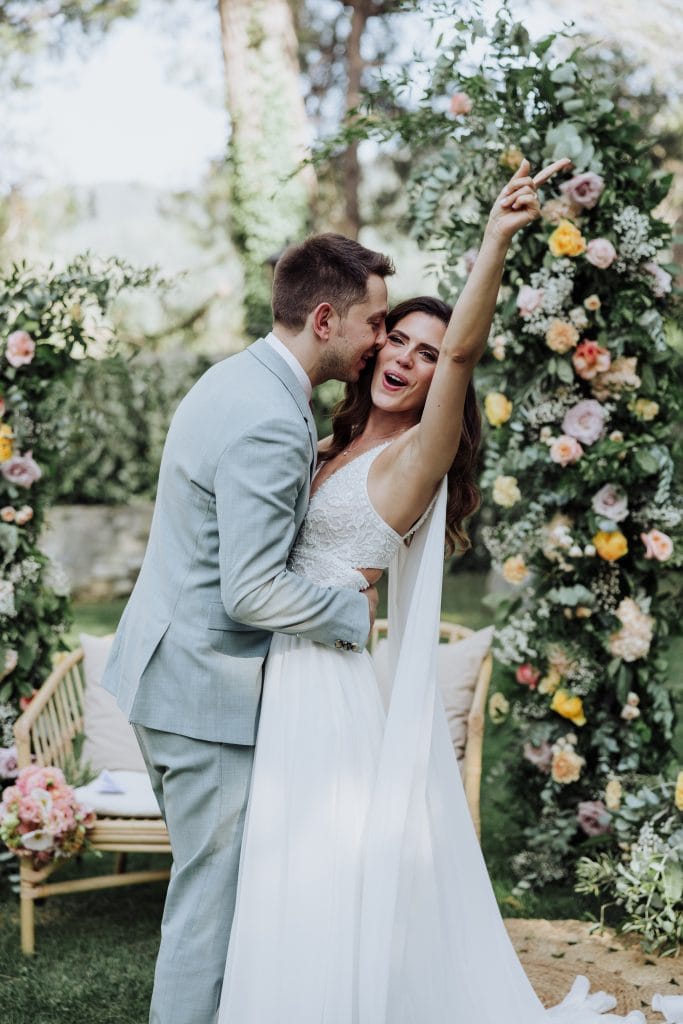 Boda al aire libre con pareja feliz en un entorno natural y floral.