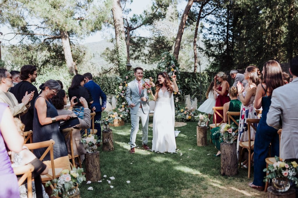 Boda al aire libre con pareja en ceremonia en un entorno natural rodeado de árboles y amigos.