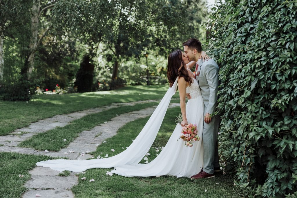 Boda en jardín con pareja feliz y romántica, rodeados de naturaleza y árboles verdes.