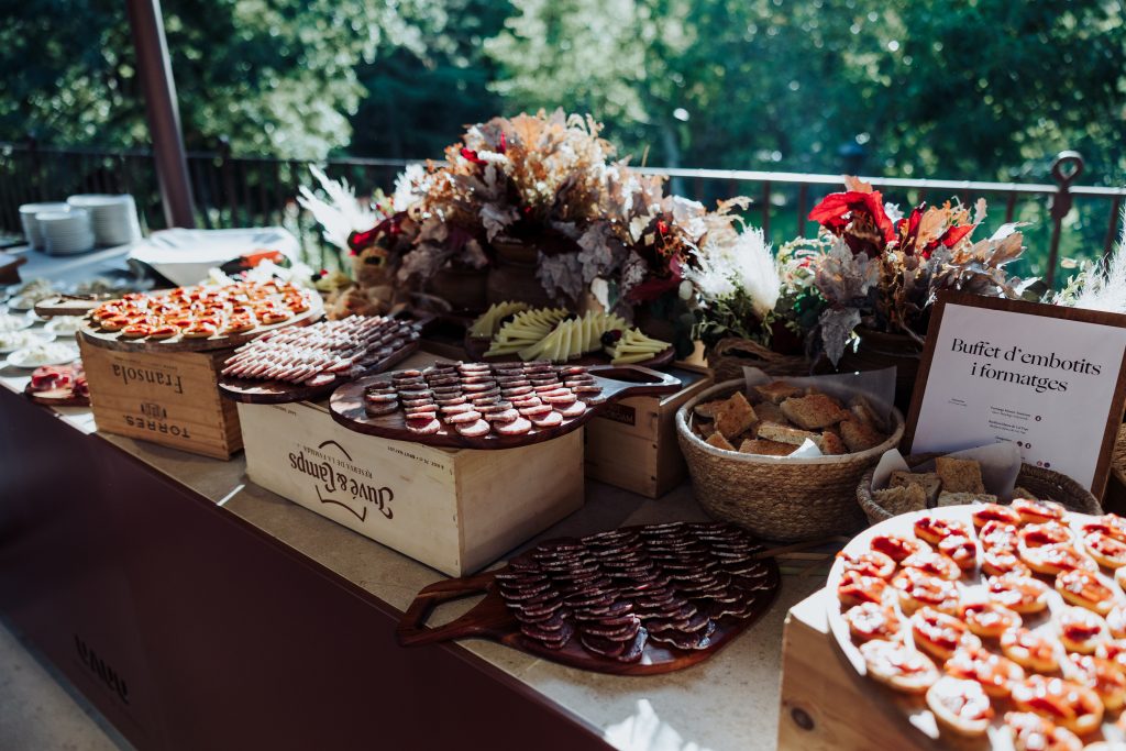 Imagen de variedad de embutidos y quesos en una mesa de boda al aire libre.