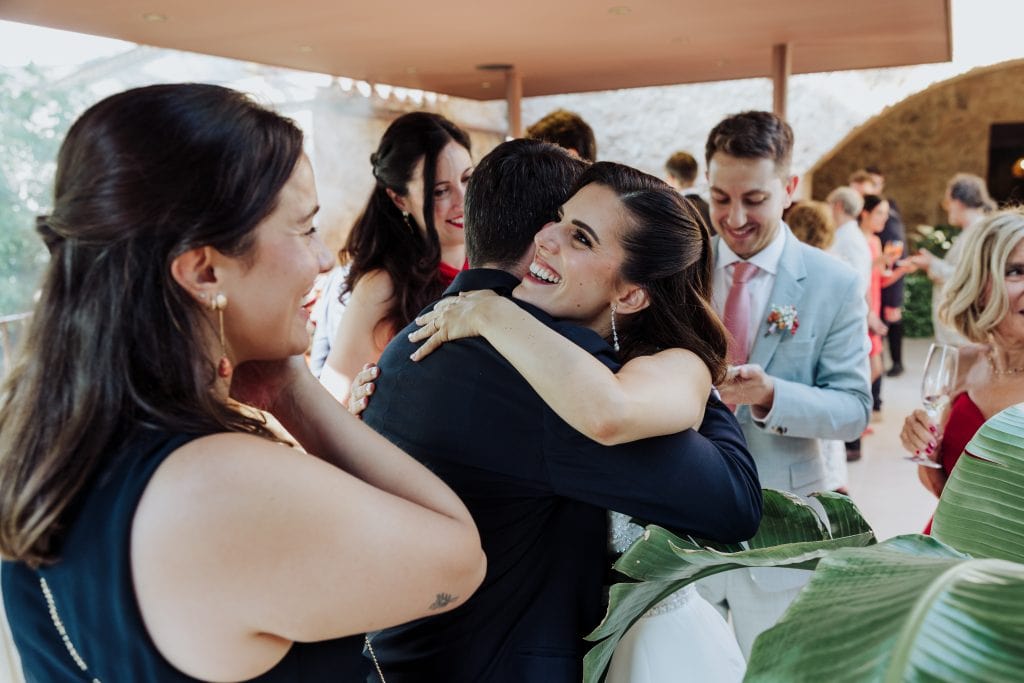 Pareja feliz abrazándose en una celebración de boda con amigos y familiares.