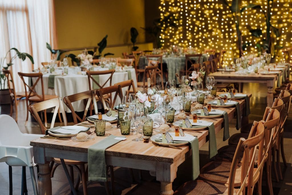 Decoración de boda rústica con mesas y luces cálidas en interior elegante.