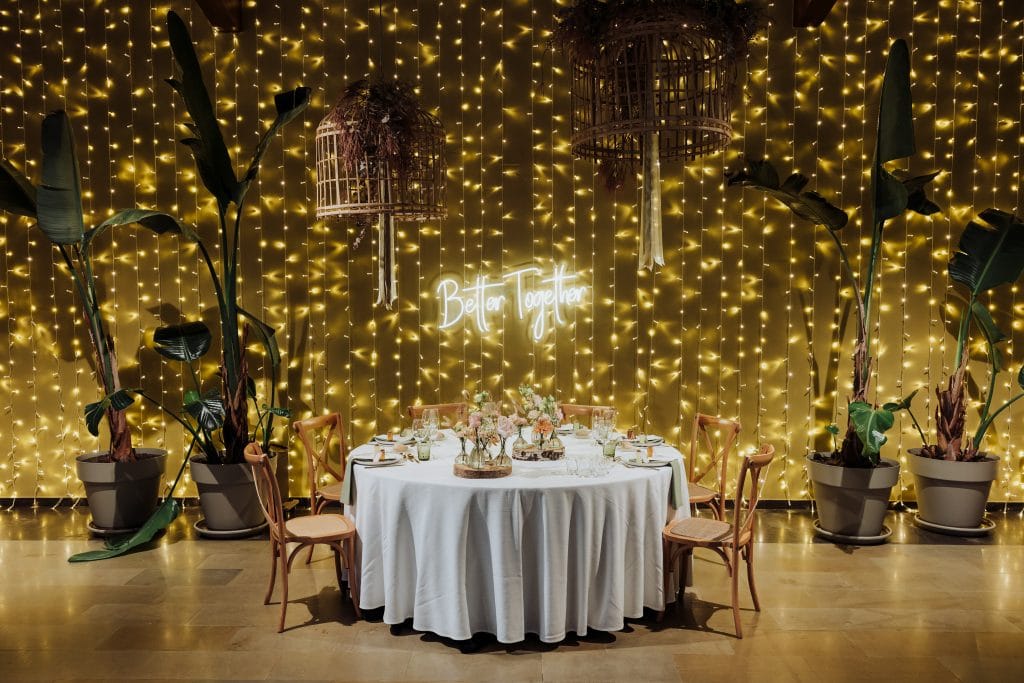 Decoración de boda con luces y plantas, ambiente íntimo y elegante para celebrar el amor.