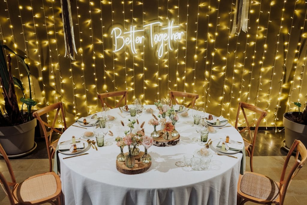 Decoración de boda con luces cálidas y cartel "Better Together" en fondo dorado.