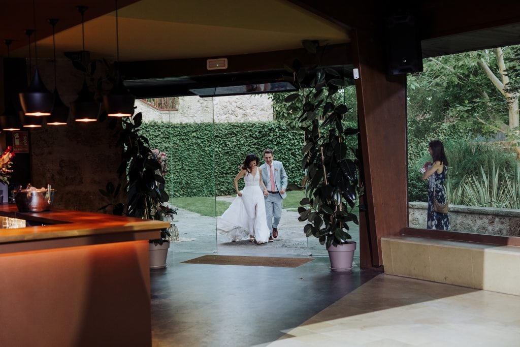 Boda en interior con vista al jardín, pareja de novios y fotógrafa en el fondo.