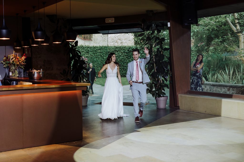 Boda en interior con pareja feliz entrando en el lugar de celebración.