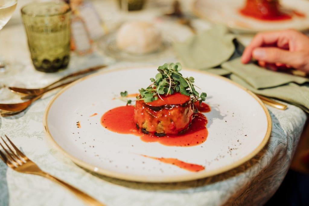 Plato gourmet con salsa y microgreens en boda elegante.