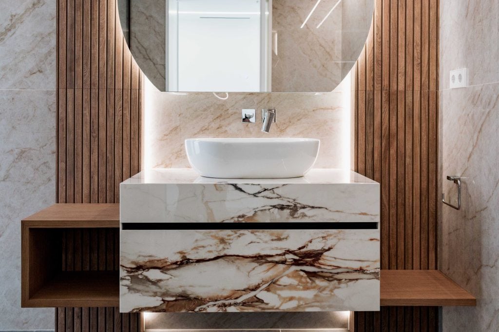Lavabo de diseño moderno en baño con paredes de madera y mármol.