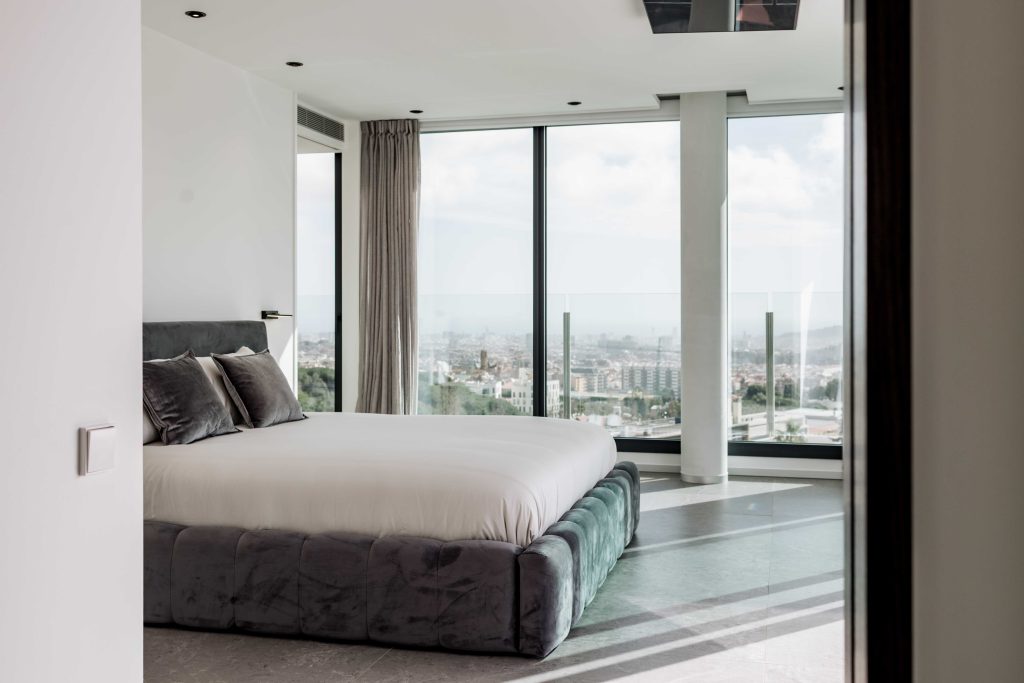 Habitación moderna con grandes ventanas y vistas panorámicas a la ciudad en un hotel de lujo.