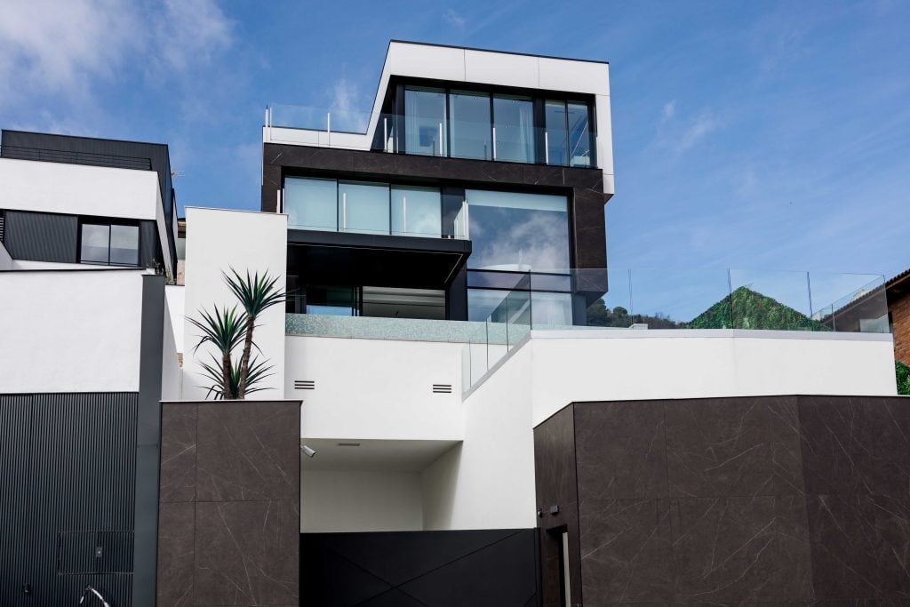 Edificio moderno y elegante con amplias ventanas y balcón en una zona urbana exclusiva.