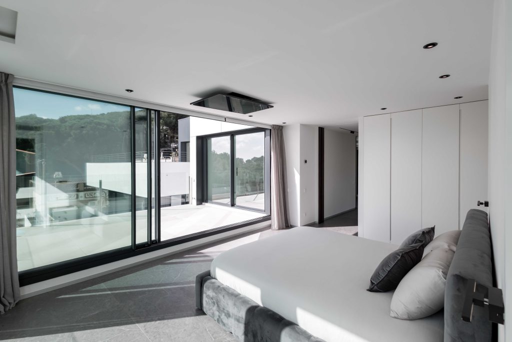 Amplia habitación moderna con puertas correderas de cristal y vistas a la montaña.