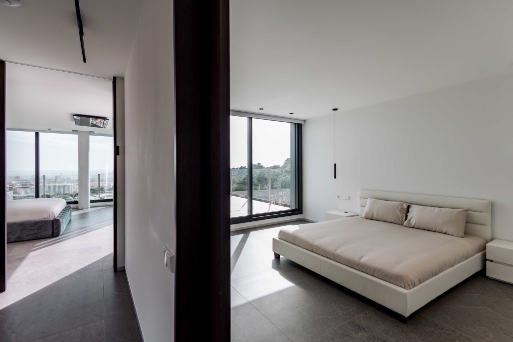 Habitación moderna minimalista con grandes ventanas y vista a la ciudad.