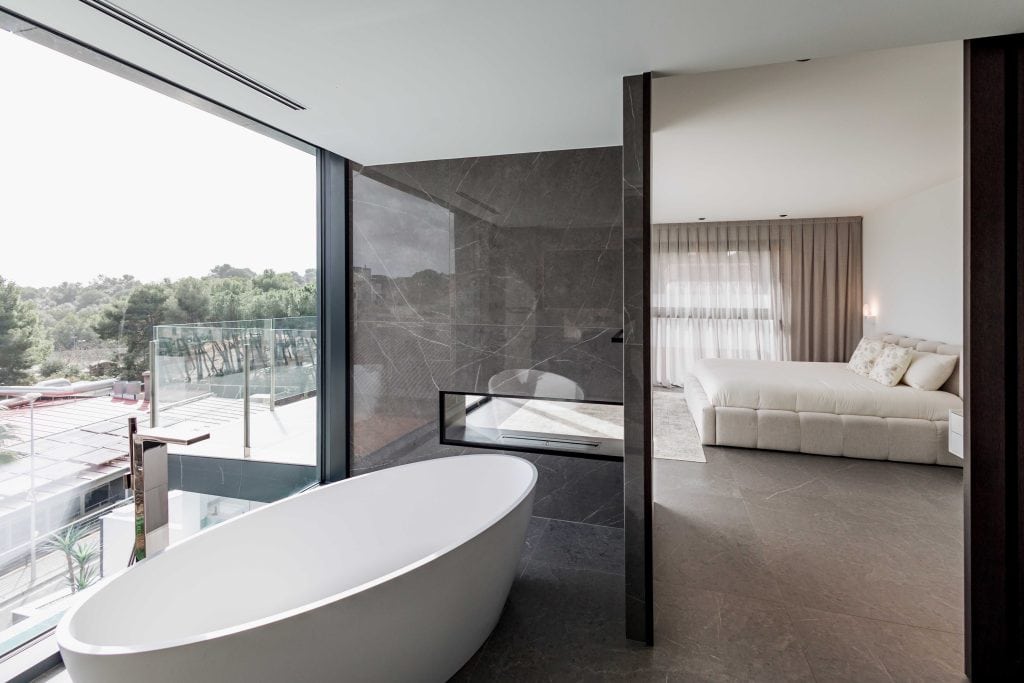 Bañera de diseño en habitación moderna con vista a la naturaleza y decoración elegante.