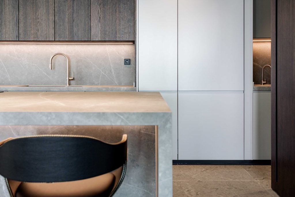 Encimera de cocina moderna con lavabo y armarios blancos en un espacio minimalista.